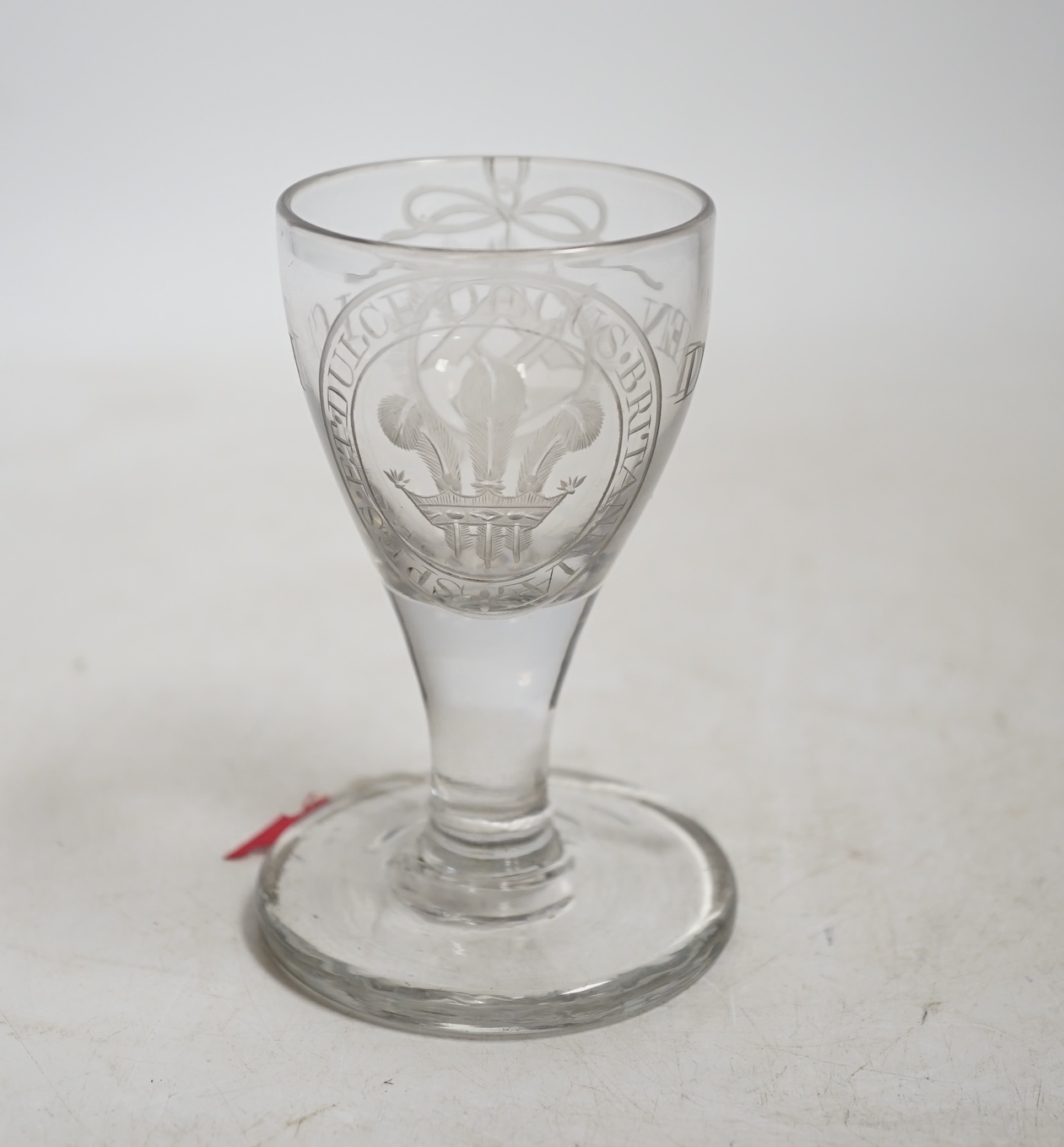 A George III Prince of Wales commemorative firing glass, early 19th century, finely wheel engraved with the Prince of Wales feathers, the motto ‘Spes. et. Dulce. Decus. Britannia’, ‘Ich Dien’ and Masonic motifs, 10.5cm h